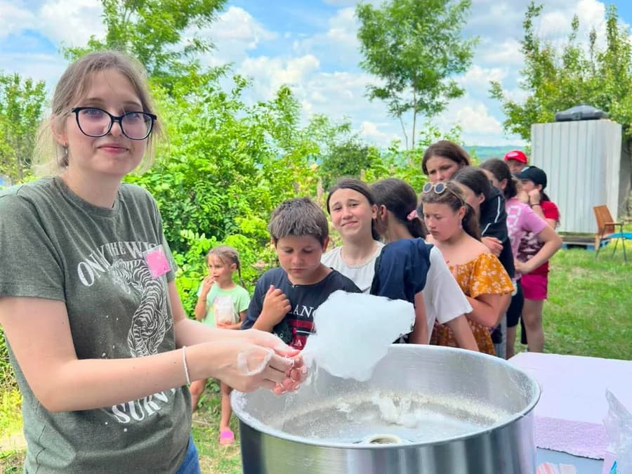 A team member spinning cotton candy for a line of village children