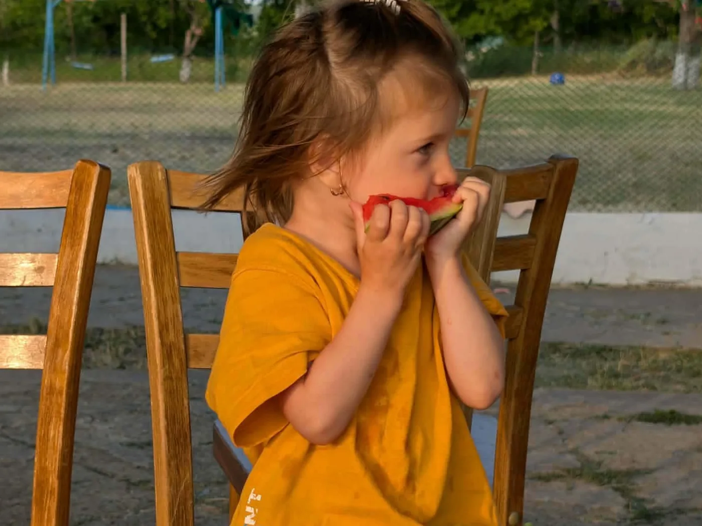 Zlata, three years old, eating a slice of watermelon at an Orphans Hands village camp